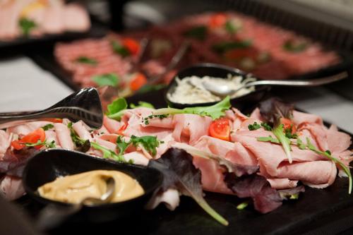 a plate of food with meat and salad with spoons at Hotel Indigo Vienna - Naschmarkt by IHG in Vienna