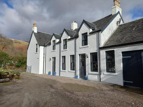 a white house with a garage on a dirt road at Orchy Bank House in Dalmally