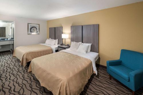 a hotel room with two beds and a blue chair at Quality Inn Fort Stockton in Fort Stockton