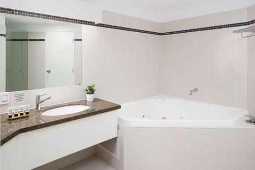 
a white bath tub sitting next to a white sink at Esplanade Hotel Fremantle - by Rydges in Fremantle
