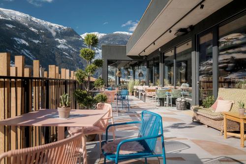 un patio con mesas, sillas y montañas en Coolnest, en Mayrhofen