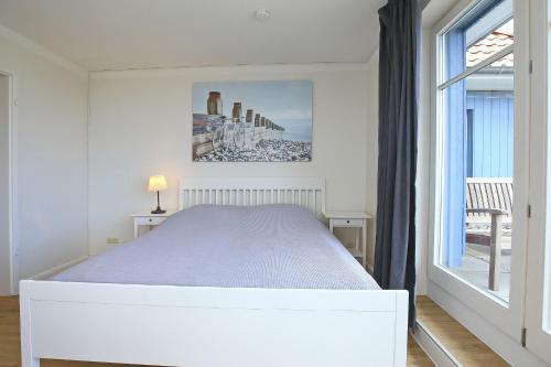a white bedroom with a bed and a window at Dünenblick Wohnung 51 in Boltenhagen