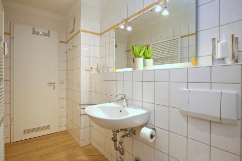 a white bathroom with a sink and a mirror at Dünenblick Wohnung 51 in Boltenhagen