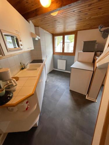Elle comprend une petite cuisine avec des appareils électroménagers blancs et des plafonds en bois. dans l'établissement Appartement en hyper centre, à Le Mont-Dore