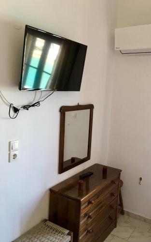 a tv hanging on a wall with a dresser and a mirror at Panorama Studios in Lipsoi