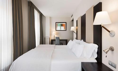 a bedroom with a large white bed and a desk at Hotel Cartagena Puerto in Cartagena