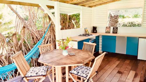 - une terrasse couverte avec une table et des chaises en bois dans l'établissement Villa Gaïa - Bungalow Ti-Zen et son jacuzzi niché dans un jardin tropical, séjour en amoureux, au Diamant