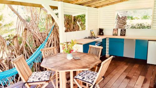 a porch with a wooden table and chairs at Villa Gaïa - Bungalow Ti-Zen et son jacuzzi niché dans un jardin tropical, séjour en amoureux in Le Diamant