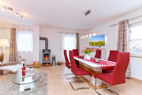 a living room with a dining table and red chairs at Ferienhaus Reethaus Koserow in Ostseebad Koserow