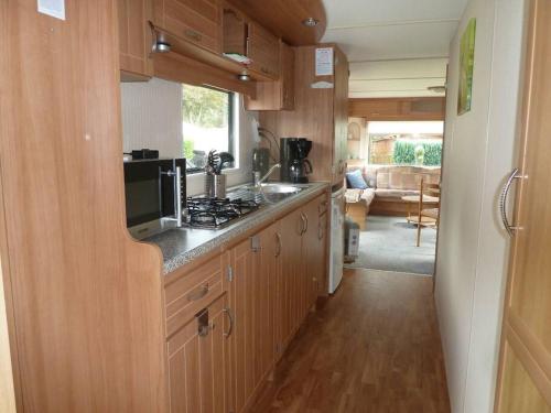 a kitchen with a stove and a microwave in a caravan at Chalet K2 op de Holle Poarte te Makkum in Makkum