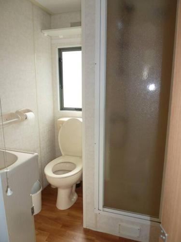 a bathroom with a toilet and a glass shower door at Chalet K2 op de Holle Poarte te Makkum in Makkum