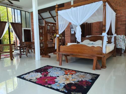 a bedroom with a canopy bed with a flower rug at Homestay ALA Riverview Lodge Kota Bharu in Kota Bharu