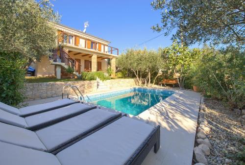 a swimming pool in front of a house at Villa Rustika in Dobrinj