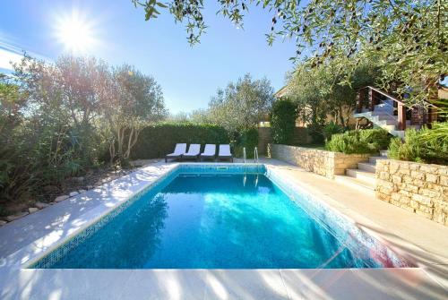 a swimming pool in a backyard with two chairs in it at Villa Rustika in Dobrinj
