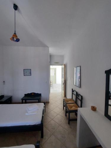a bedroom with a bed and chairs in a room at ISALOS ROOMS ON THE BEACH in Serifos Chora