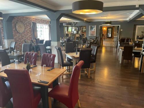 a restaurant with wooden tables and chairs in a room at Littleover Lodge Hotel in Derby