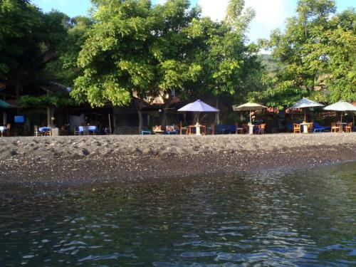 a body of water with tables and umbrellas at Blue Star Bungalows & Cafe in Amed