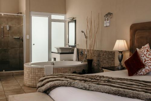 een slaapkamer met een bad, een bed en een wastafel bij Artemis Hotel Swakopmund in Swakopmund