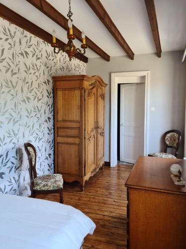 - une chambre avec un lit, une armoire en bois et un bureau dans l'établissement Maison en pierres entre terre et mer.., à Neuville-en-Beaumont