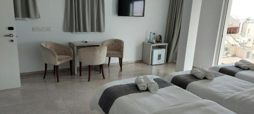 a hotel room with two beds and a table and a dining room at La Veranda Hotel in Larnaka
