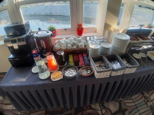 einen Tisch mit Tassen und Tellern sowie eine Kaffeemaschine in der Unterkunft Schronisko na Wyspie in Breslau