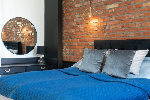 a bedroom with a blue bed with a brick wall at Oliwa Am Calsberg 5a in Gdańsk