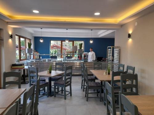 a restaurant with tables and chairs and a man in the kitchen at Pensiunea Bella Praid in Praid