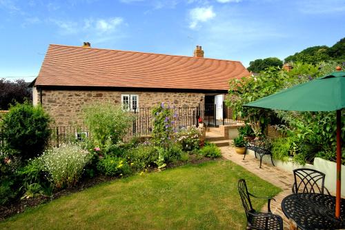 a house with a garden and an umbrella at Stone Barn in Minehead