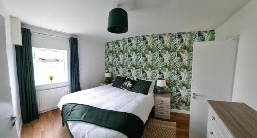 a bedroom with a bed with a green wall at Bungalow fully renovated 2022 close to slob lands and beach in Ballygarrett