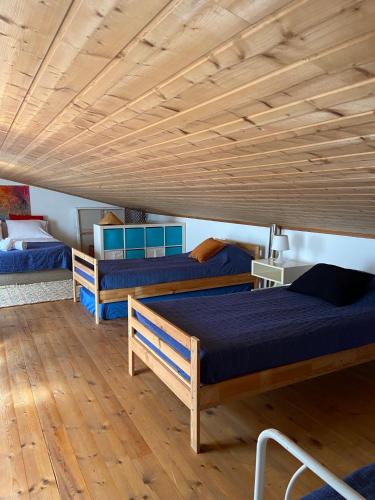 three beds in a room with a wooden ceiling at Casa Pedralva in Vila do Bispo