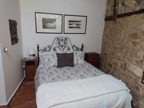 a bedroom with a bed and a stone wall at Las Casitas del Salado - La Casita roja in Santamera