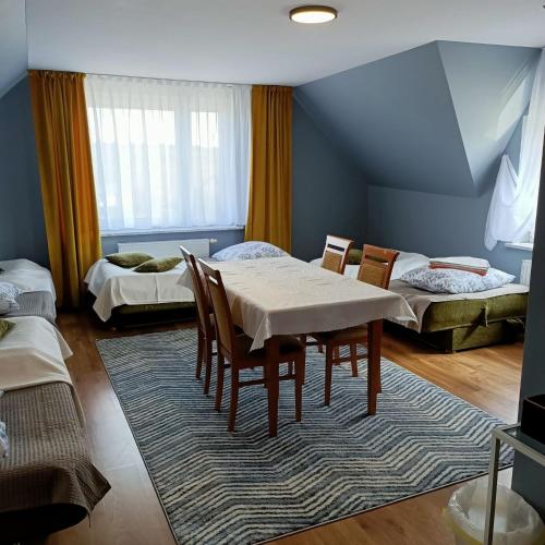 a room with a table and chairs and two beds at Willa Różana in Wola Kalinowska