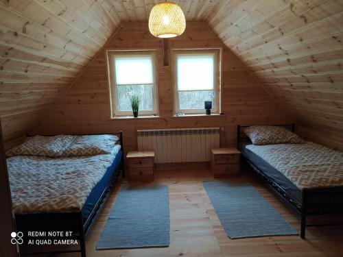 two beds in a attic room with two windows at Gajówka Żłobek in Żłobek
