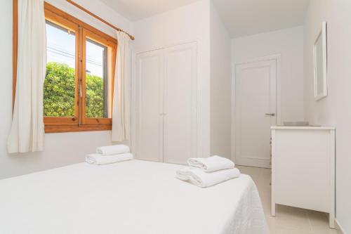 a white bedroom with a bed and a window at Villa Marina -Cala EnPorter- in Cala'n Porter