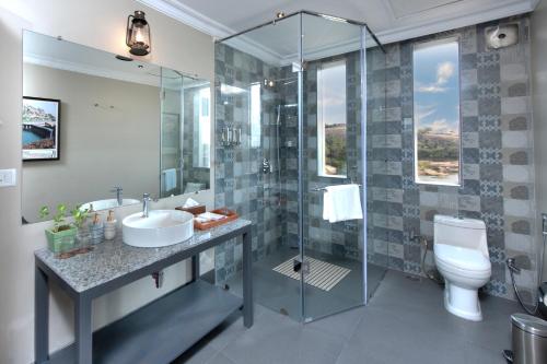 a bathroom with a shower and a sink and a toilet at WelcomHeritage Cheetahgarh Resort & Spa in Bera