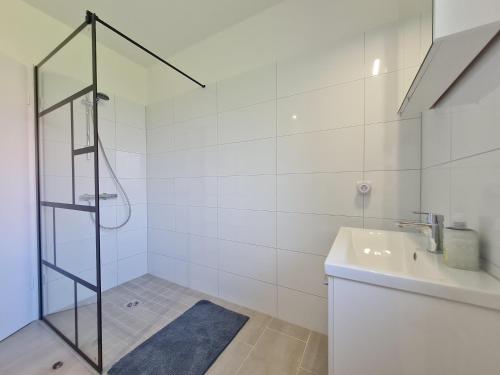 a white bathroom with a shower and a sink at Ferienhaus Vergissmeinnicht in Garding