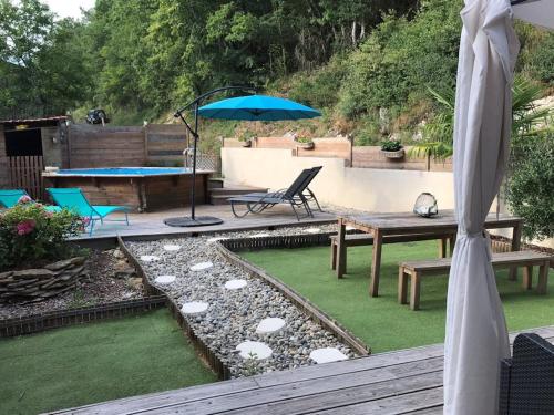un patio avec une table et un parasol dans l'établissement Maison de Charme l Etoile, à Saint-Vincent-de-Cosse