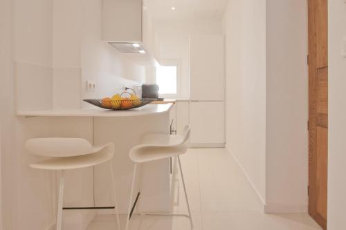 - une cuisine blanche avec deux tabourets et un bol de fruits dans l'établissement Studio cozy sur la Marina de Bonifacio, à Bonifacio