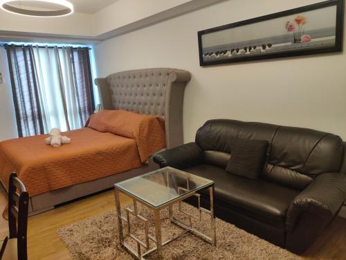 a living room with a leather couch and a bed at Abreeza Condo T2-2820 in Davao City