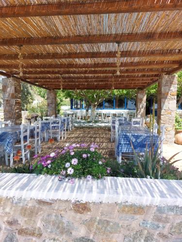 a patio with tables and chairs and a wooden pergola at ISALOS ROOMS ON THE BEACH in Serifos Chora