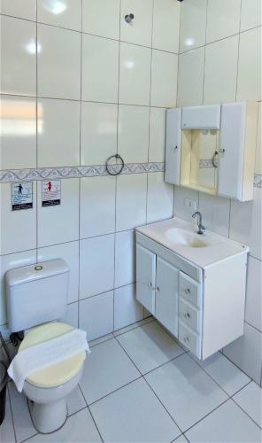 a white bathroom with a toilet and a sink at Encantos do Lázaro in Ubatuba