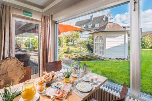 Un comedor con una mesa y un gran ventanal. en BB Landhotel Hütter, en Meschede