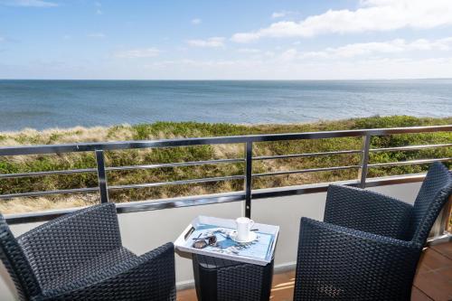 a balcony with chairs and a table and the ocean at Wattenblick in List