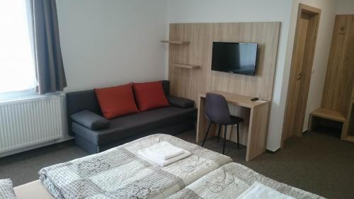 a hotel room with a couch and a tv at Penzion Skalka in Skalka