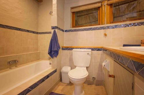 a bathroom with a toilet and a tub and a sink at Lokuthula Lodge in Victoria Falls