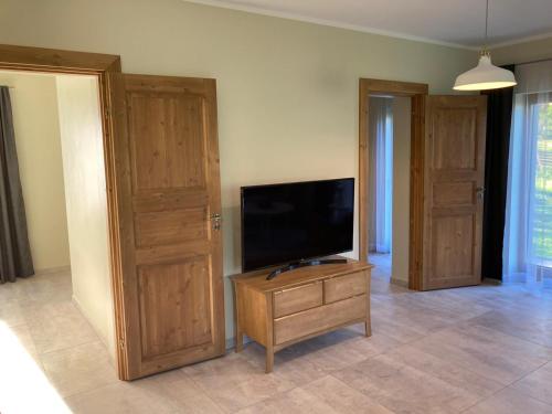 a living room with a flat screen tv and a wooden door at LUČI jūras apartamenti in Roja