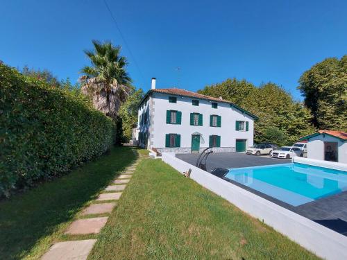 une maison blanche avec une piscine devant dans l'établissement Gite Moulin Urketa, à Ayherre