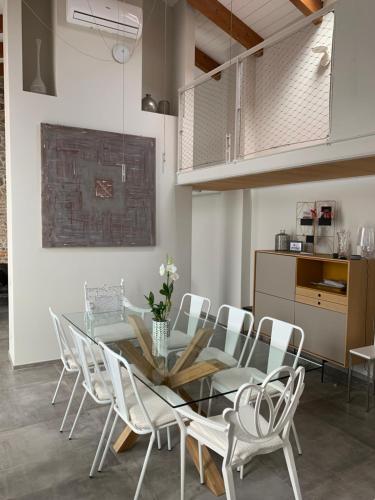 Un comedor con una mesa de cristal y sillas blancas. en Horse Shoe House, en Chiaverano
