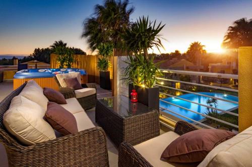 a balcony with wicker furniture and a swimming pool at Penthouse Duplex Rooftop Jacuzzi 4 Rooms 6 beds 8 Persons in Cascais