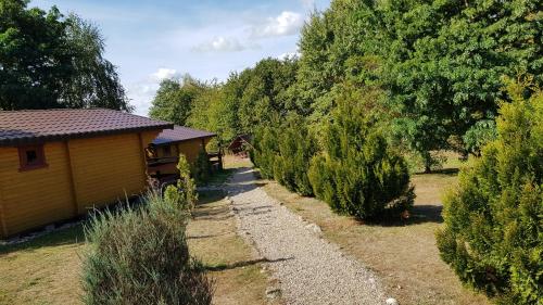 a house with a row of trees in a yard at Domki Letniskowe Kalem in Zabin